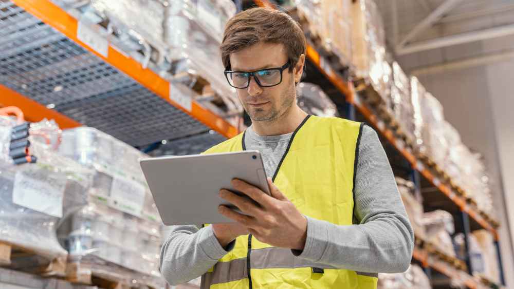 Warehouse worker using a tablet to analyze inventory data, representing TMMD Consulting’s data warehousing and business intelligence services.